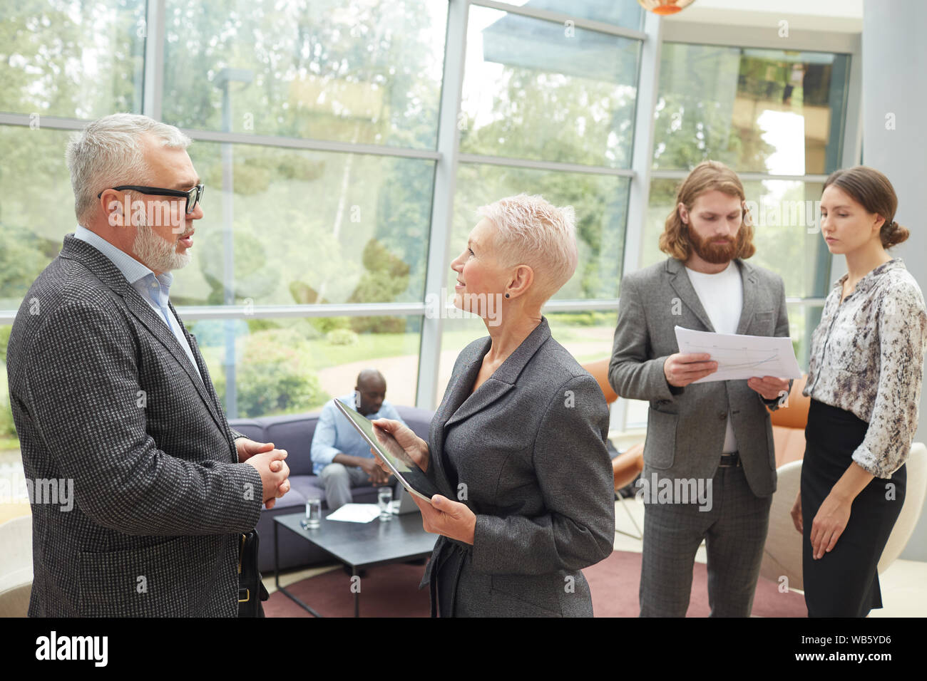 Ritratto di gruppo eterogeneo di uomini di affari che lavora nella sala del moderno edificio si concentrano su due senior manager in primo piano, spazio di copia Foto Stock