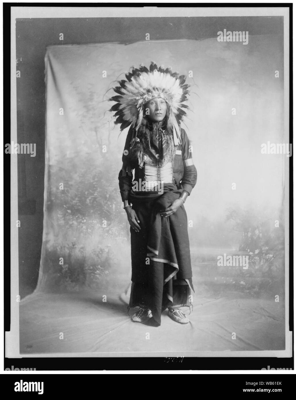 Maglia Eagle, Indiani Sioux di intera lunghezza verticale, rivolto leggermente a destra, in piedi di fronte a uno sfondo studio Foto Stock
