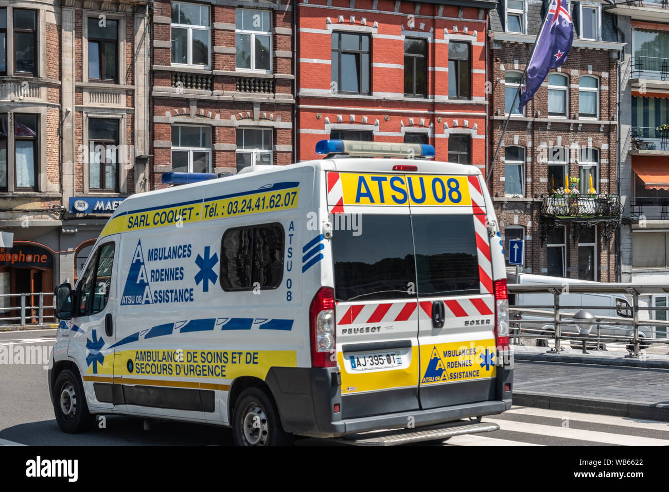 Dinant, Belgio - 26 Giugno 2019: il bianco e il giallo ambulanza van su Charles de Gaule Bridge. Pub e ristoranti nel retro. Foto Stock