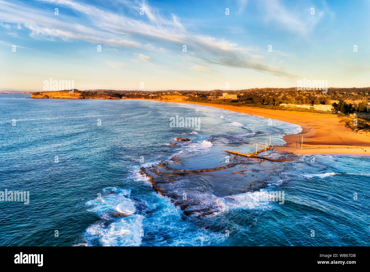 Giallo sabbia spiaggia di Mona Vale sobborgo a nord di Sydney con rock pool in sospeso su una punta di altopiano di arenaria in oceano Pacifico - aerial vi Foto Stock