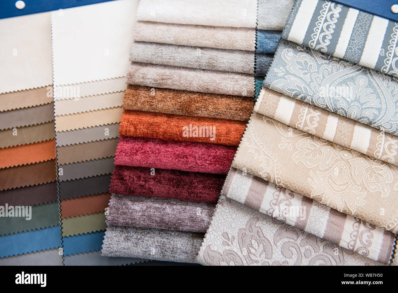 Una selezione assortita di tessuti di campioni di colore o di campioni per la decorazione degli interni con diverse texture e i modelli in un overhead telaio completo backgrou Foto Stock