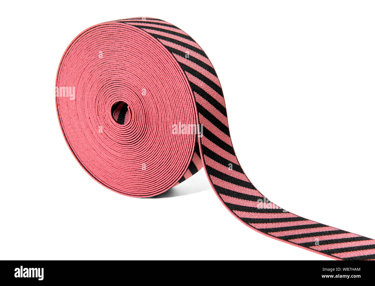 Rotolo di decorativo nastro elastico in rosso e nero con alternanza di strisce diagonali visualizzate in corrispondenza di un angolo su bianco con spazio di copia Foto Stock