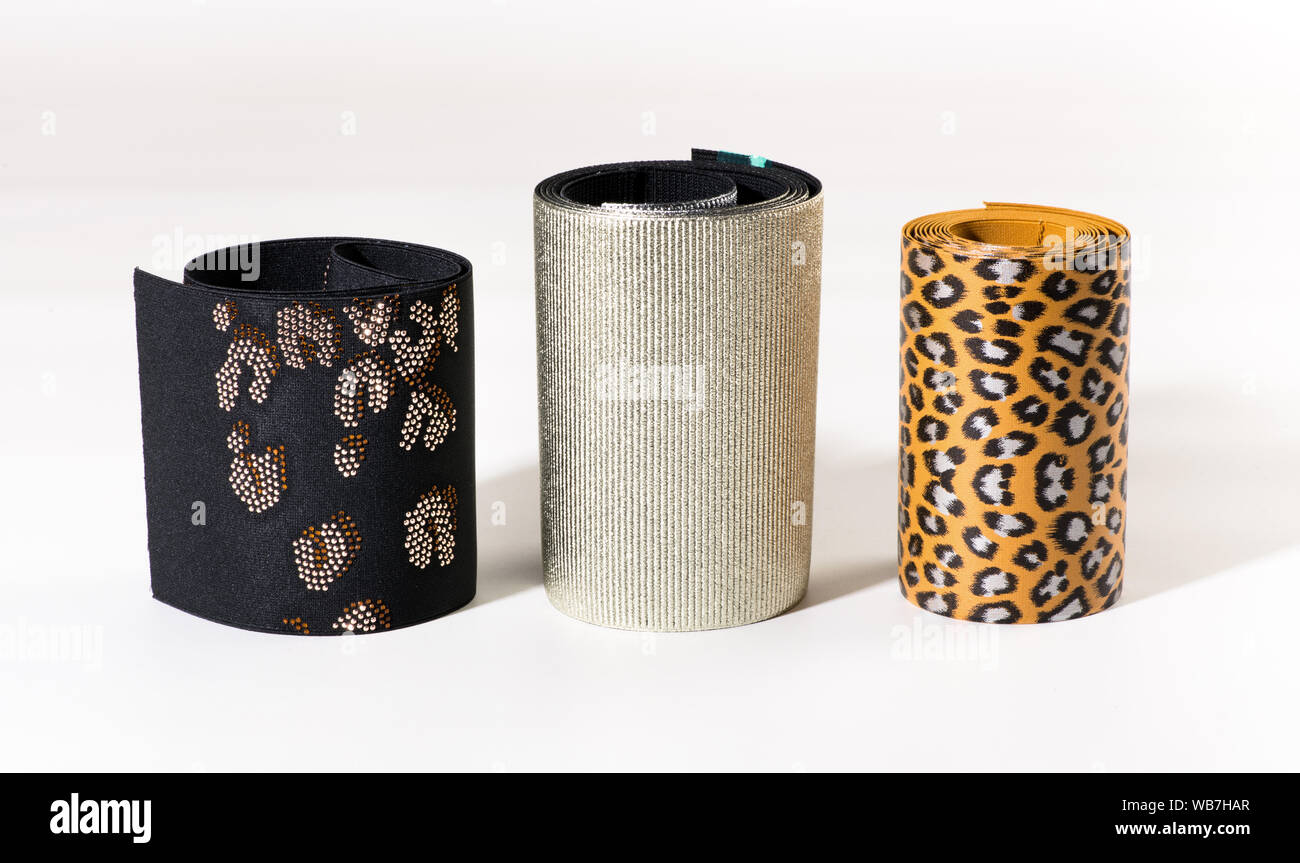 Tre rotoli larghi di motivi decorativi nastri elastici o bande con leopard stampa, rivestiti di consistenza e di pattern su nero in posizione eretta su bianco Foto Stock