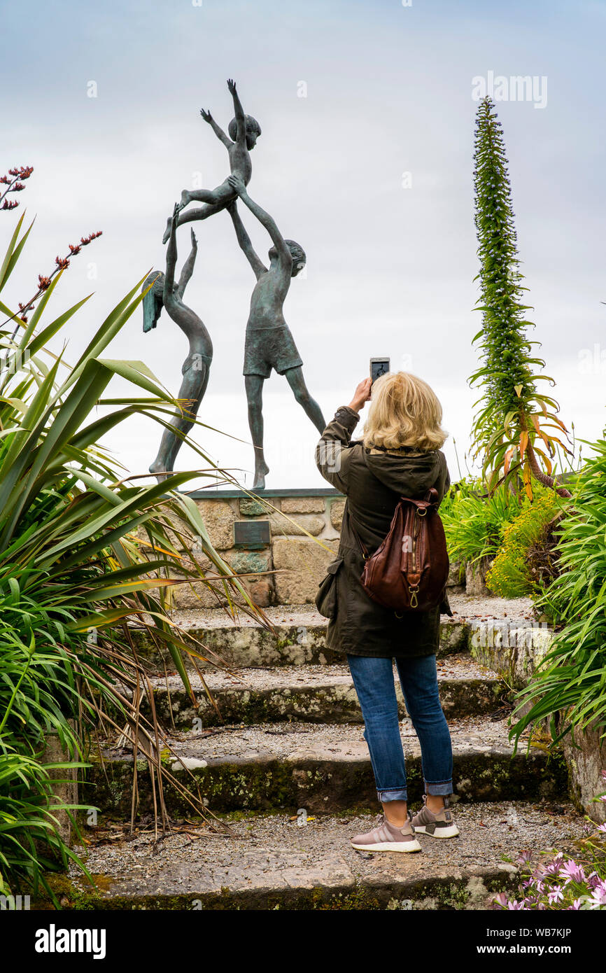 Regno Unito, Inghilterra, isole Scilly, Tresco, Abbey Gardens, visitatore tenendo la fotografia della Tresco bambini, 1990 scultura di David Wynne, sul telefono cellulare Foto Stock