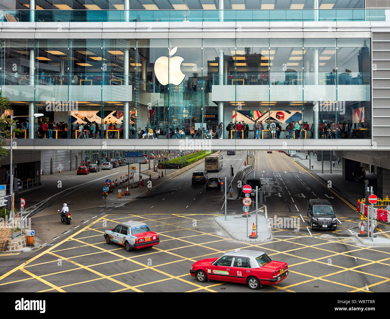 Red taxi passando dagli Apple Store in centrale. Hong Kong, Cina. Foto Stock