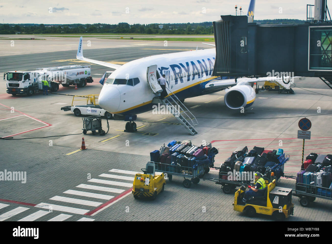 / Danzica Polonia - 4 Agosto 2019: Controllo trasporto bagagli cargo essendo guidato verso un aereo Ryanair sulla pista a Gdansk airport Foto Stock