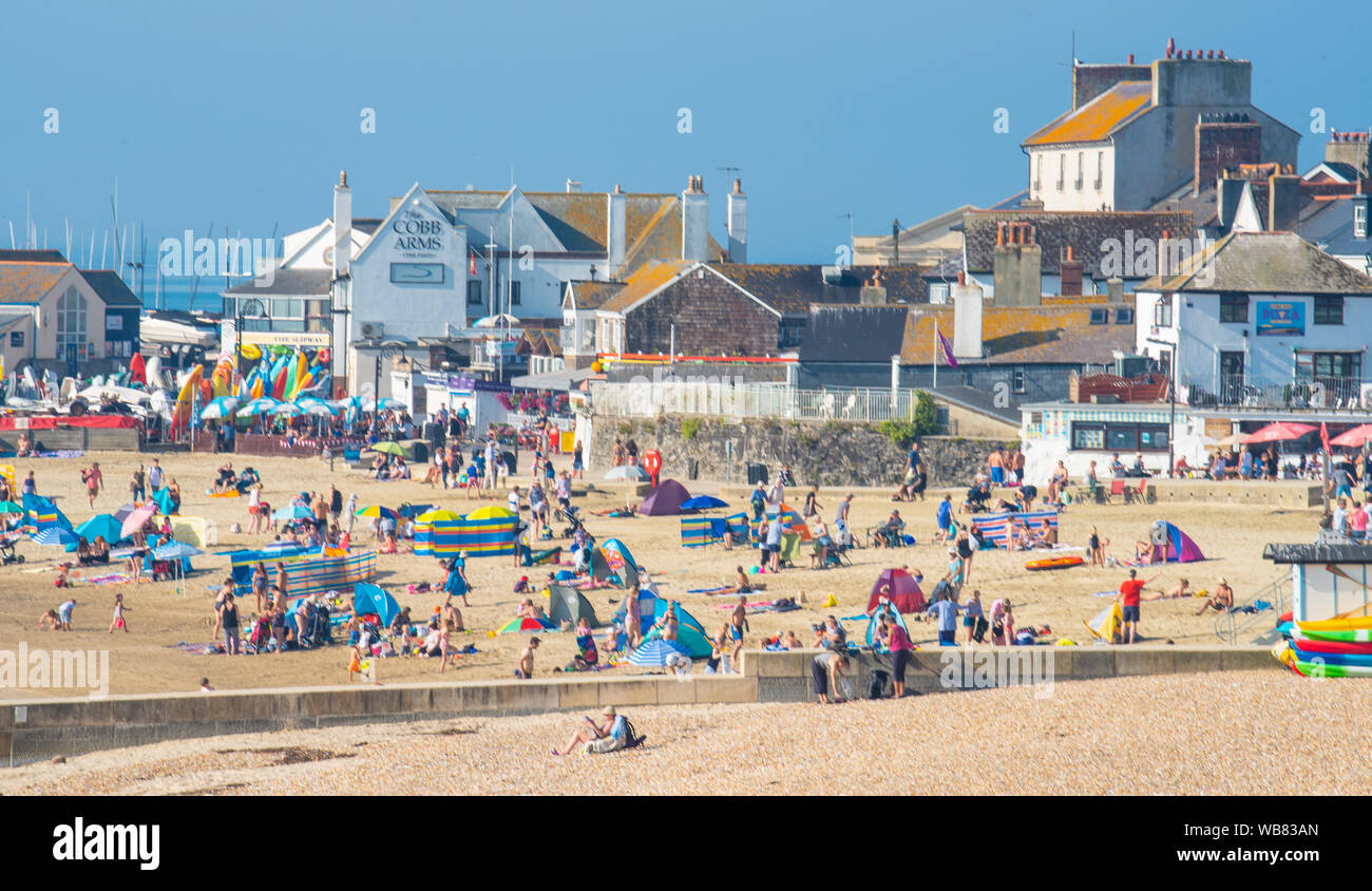 Lyme Regis, Dorset, Regno Unito. 25 Ago, 2019. Regno Unito: Meteo Blisteringly sole caldo e calore swelterig come le temperature si elevano ulteriormente su Bank Holiday Domenica. Beachgoers fissare un posto sulla spiaggia di sabbia a pittoresco Lyme Regis prima di bank holiday folla ha colpito la famosa località balneare. Credito: Celia McMahon/Alamy Live News Foto Stock