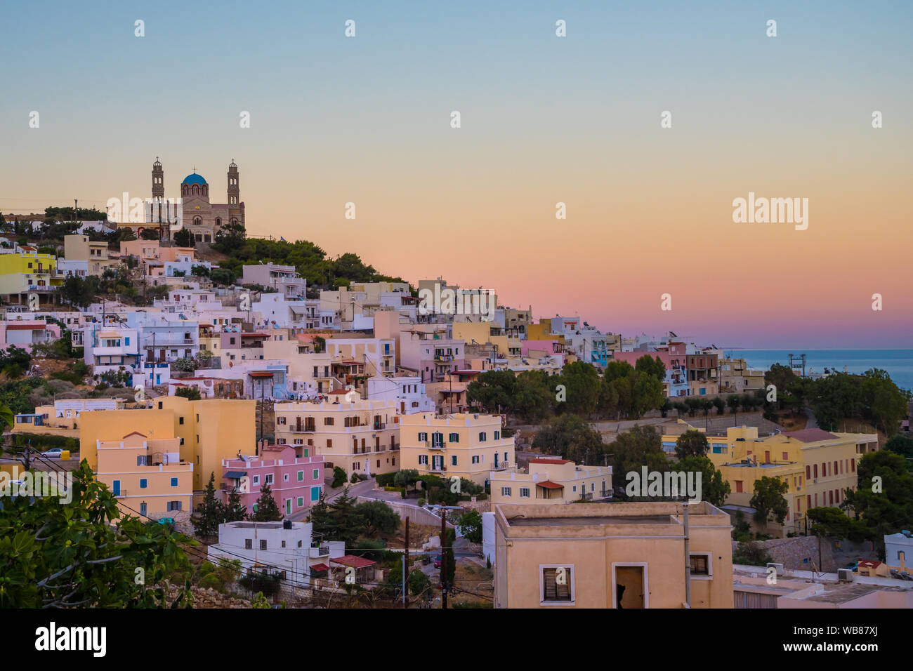 Vista panoramica della città di Ermoupoli dell'isola di Syros nelle Cicladi, Grecia. Vista sulle case colorate, il porto e la chiesa ortodossa Anastaseos al tramonto Foto Stock