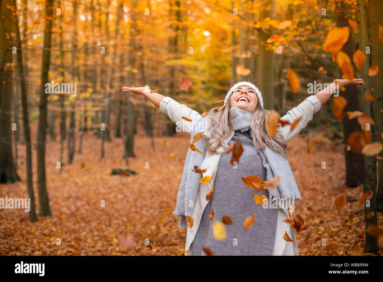 Ragazza che cammina nel parco in autunno e sorride a braccia aperte Foto Stock