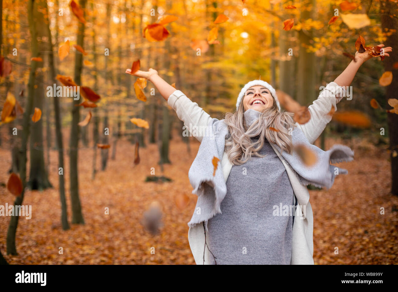 Ragazza che cammina nel parco in autunno e sorride a braccia aperte Foto Stock