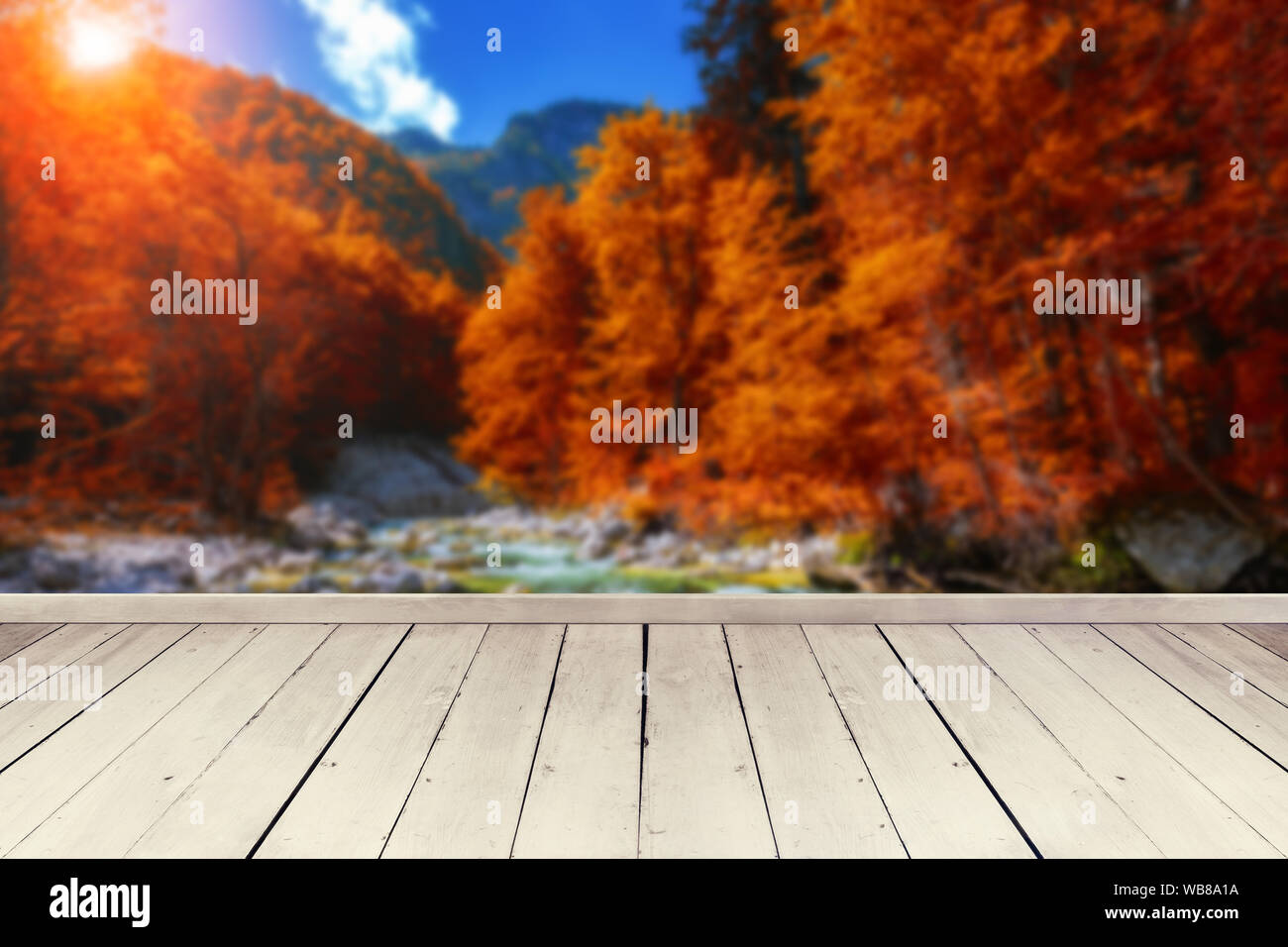 Svuotare tavolo in legno per il product placement o montaggi con particolare attenzione al tavolo in primo piano sfocato paesaggio autunnale in background con waterfa Foto Stock