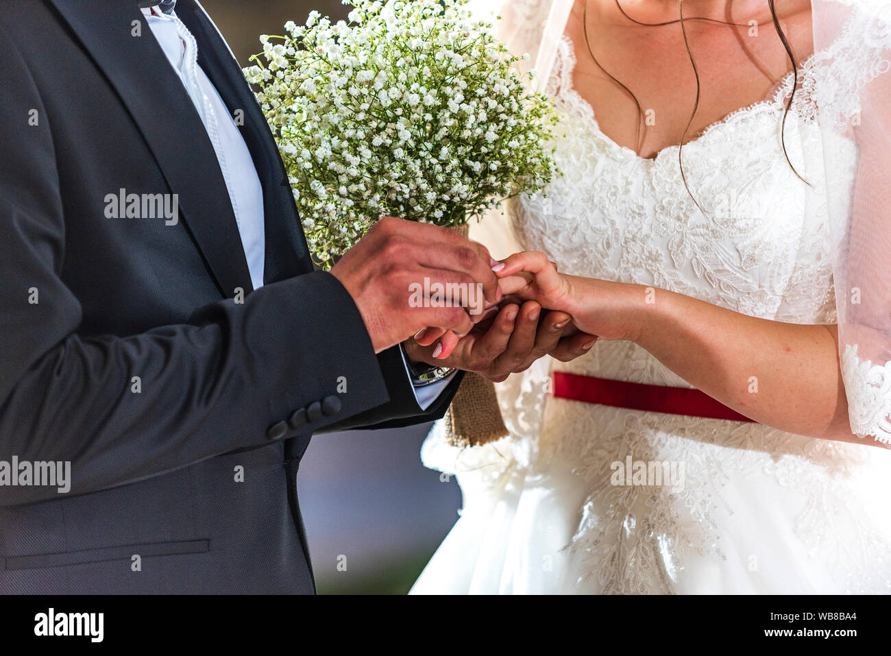 Sposi anelli di exchange, lo sposo mette l'anello sulla sposa la mano nel matrimonio ufficio del registro di sistema Foto Stock