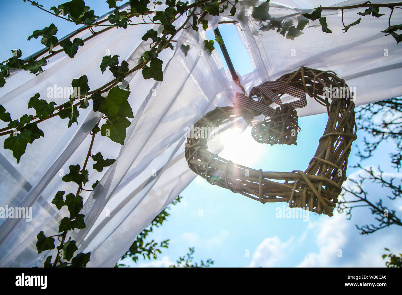 Il dettaglio di un matrimonio tradizionale decor. Il cuore di vimini con un piccolo cuore interno contro il sole. Foto Stock