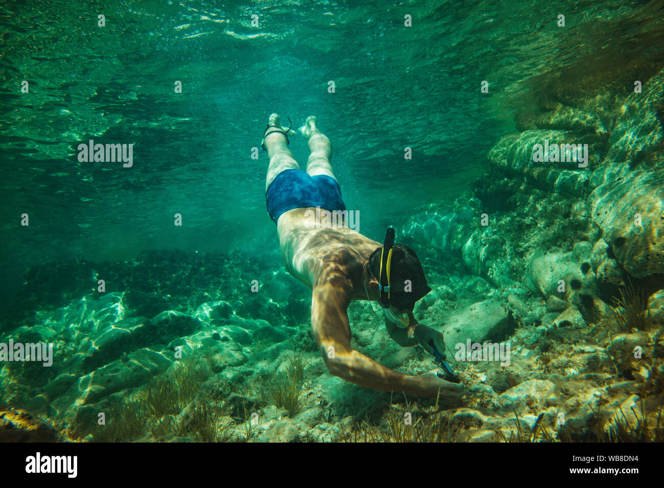 Uomo bello divertirsi in vacanza estiva ed esplorare il fondale durante le immersioni subacquee in mare. Foto Stock