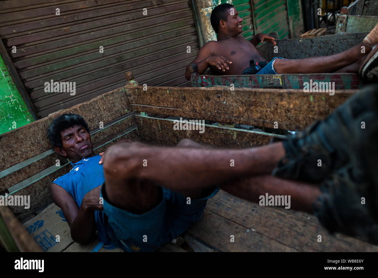 Vettori Afro-Colombian giacciono nel loro carrelli di legno dopo un giorno intero turno di lavoro nel mercato di Bazurto a Cartagena, Colombia. Foto Stock