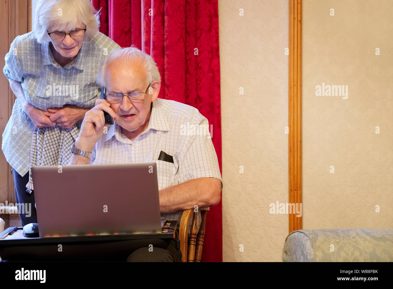 Senior coppia di anziani al pc portatile e sul telefono per aiutare seguente email cyber attacco di virus per frode della banca Foto Stock