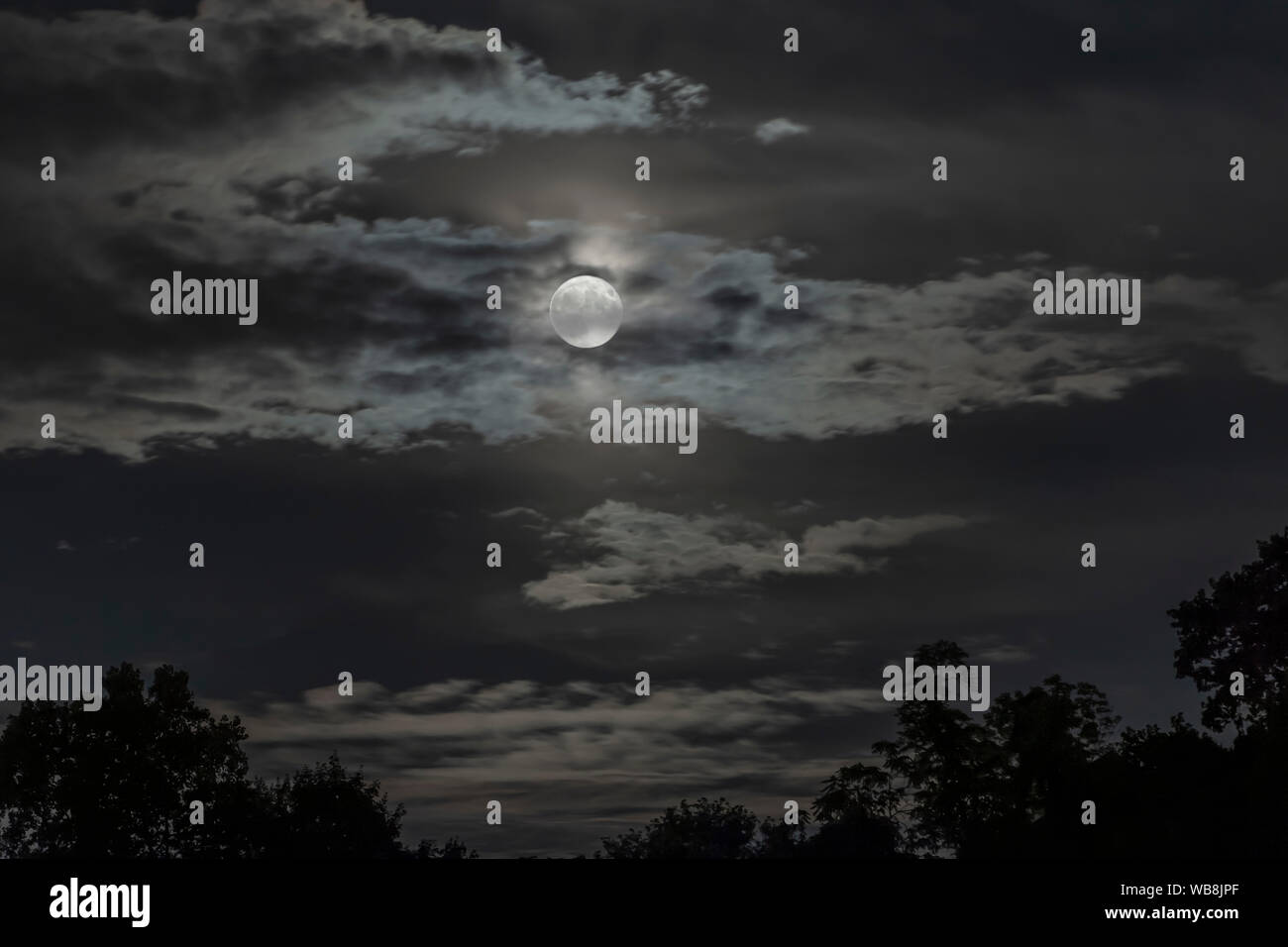 Luna piena parzialmente nascosto da nuvole Foto Stock