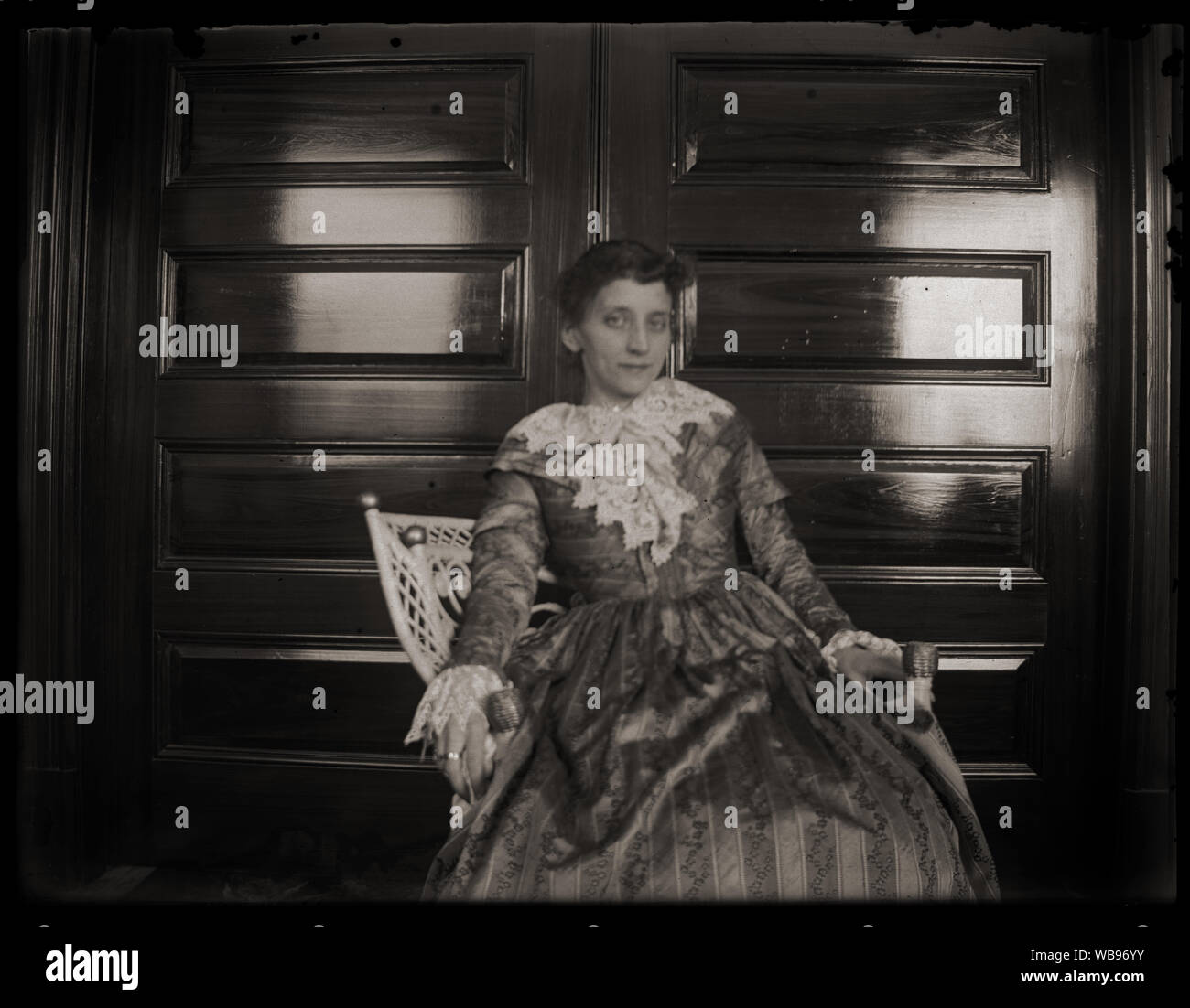 Ritratto di donna sorridente nella sedia di vimini indossando storico stile coloniale abito. Inizio periodo edoardiano fotografia amatoriale, scandita dall'originale 3x4 pollici lastra di vetro negativo circa primi 1900s. Foto Stock