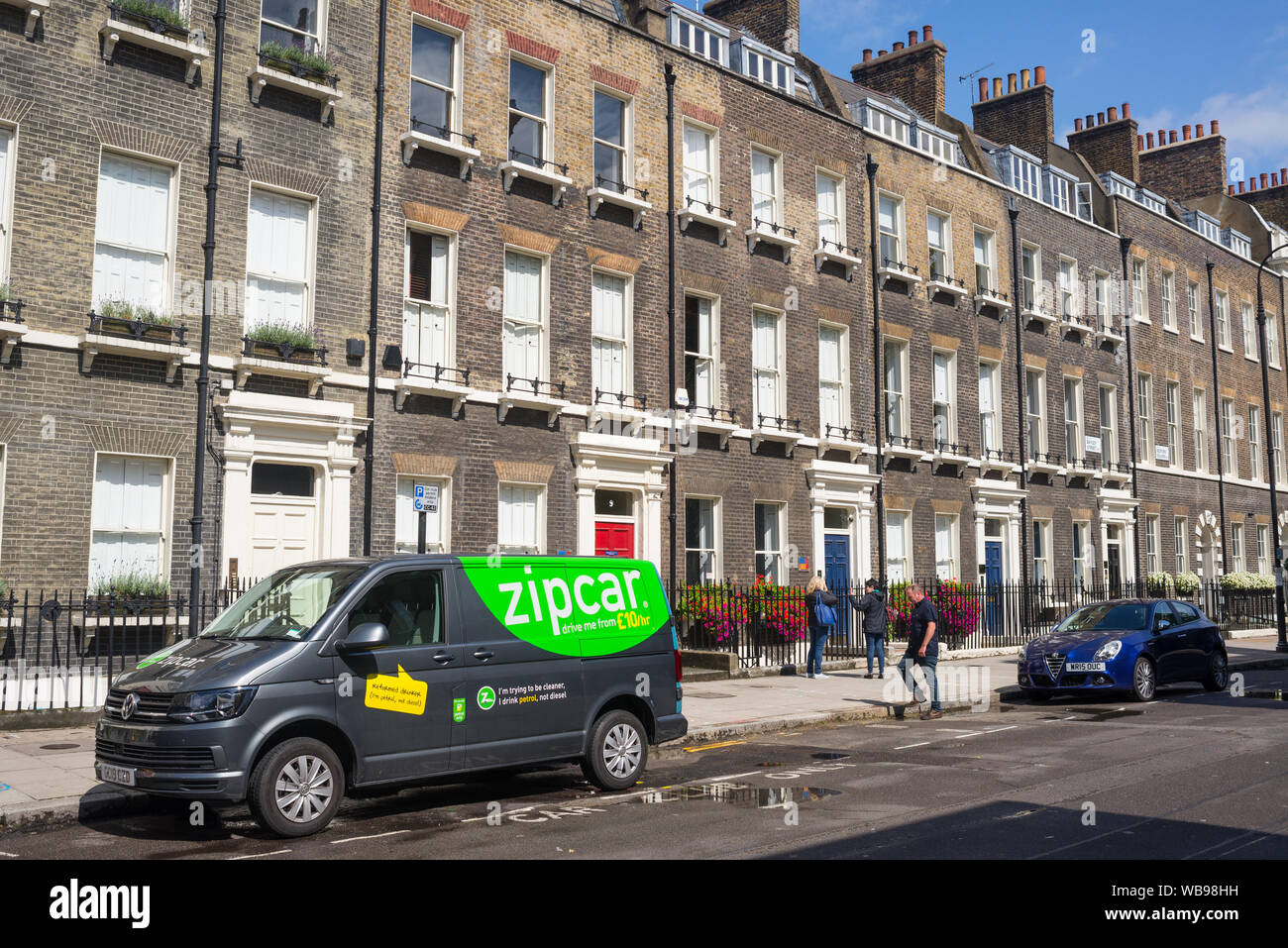 London, Regno Unito - Agosto 2019: Zipcar van per la condivisione di auto parcheggiata in una strada locale con proprietà di lusso tenement case in stile georgiano di stile britannico in centr Foto Stock