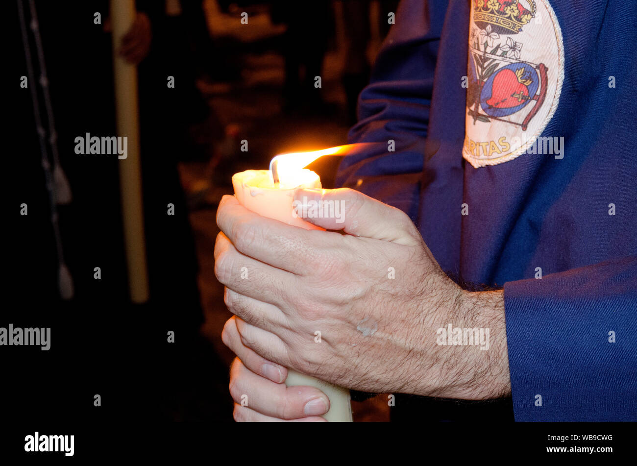 Primo piano delle mani di un penitente nazareno tenendo la sua candela durante una processione. La Settimana Santa, Siviglia, Andalusia, Spagna. Processione notturna del Foto Stock
