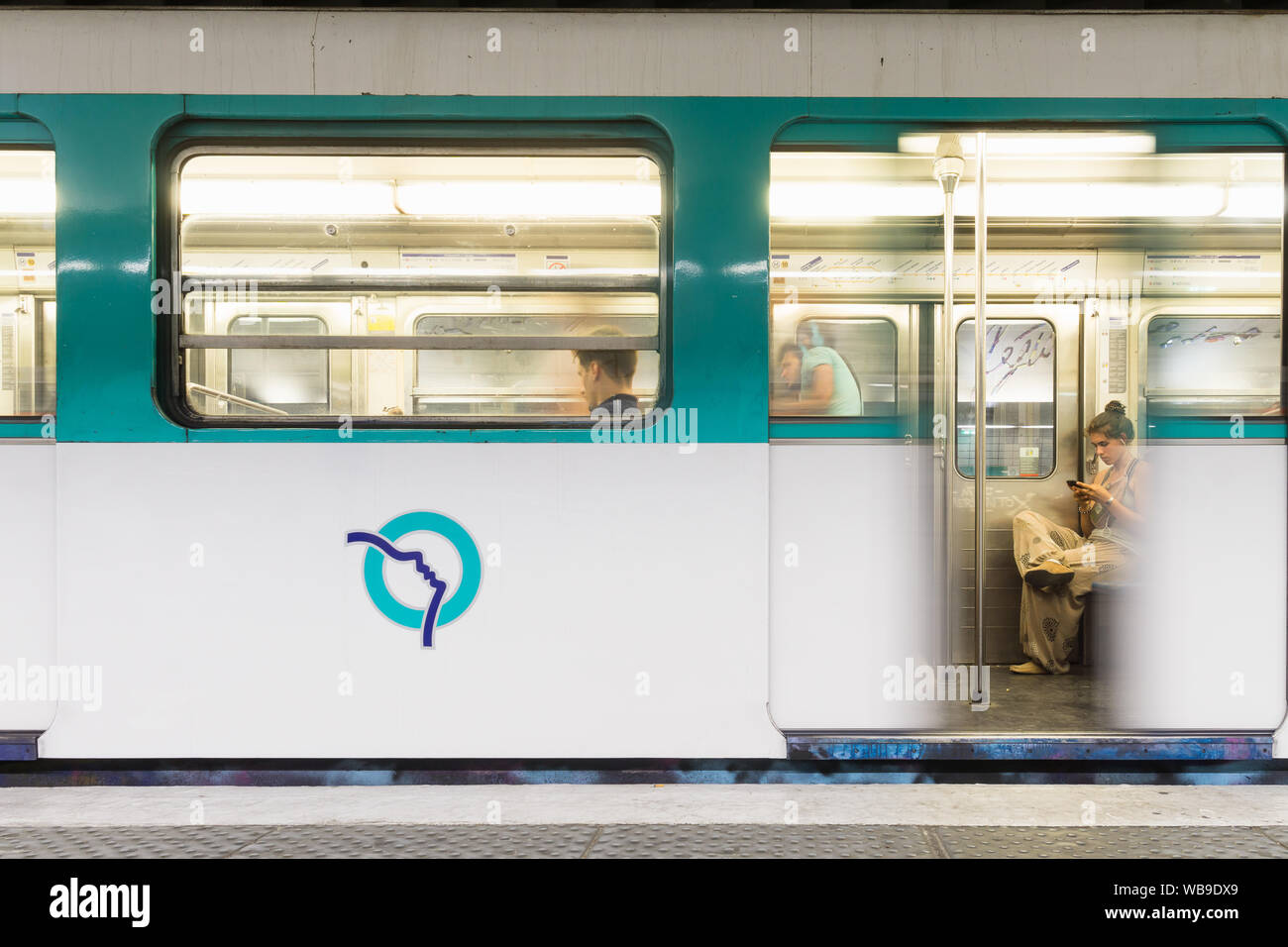 Parigi la scena della metropolitana - una donna che guarda il telefono mentre è in attesa per il treno in partenza. In Francia, in Europa. Foto Stock