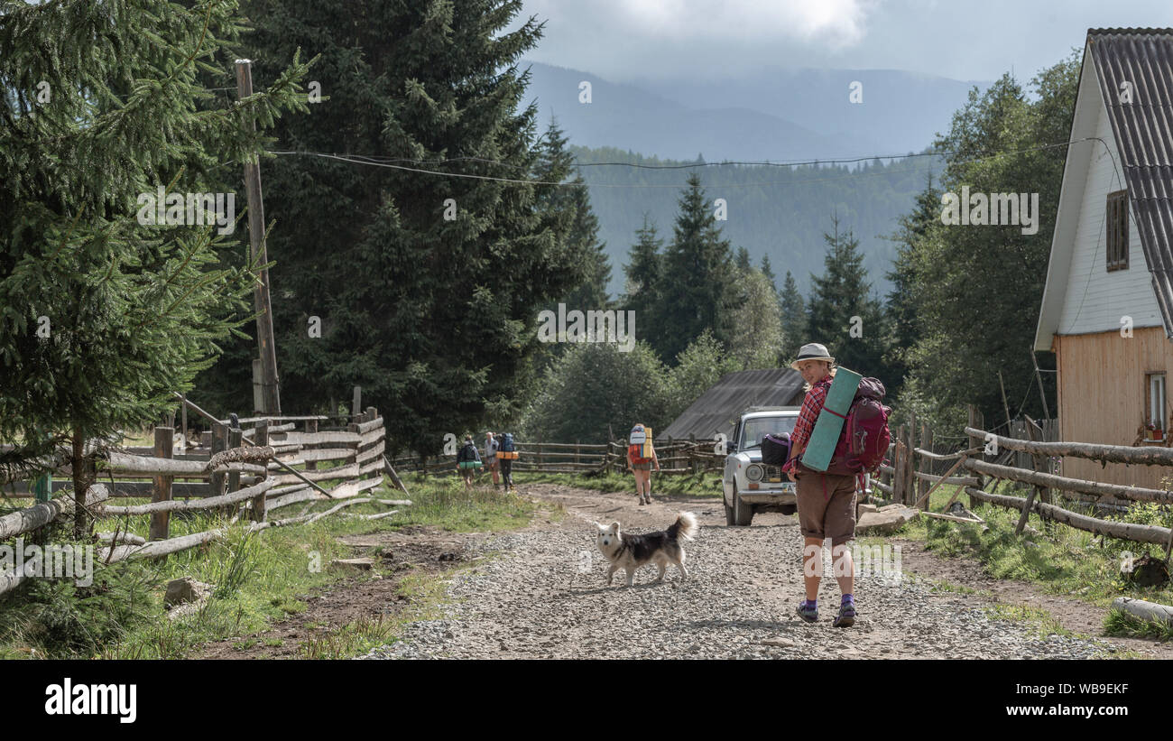 Ragazza di viaggio con zaino a piedi per incontrare nuovi avventuriero e il nuovo cammino con il cane Foto Stock