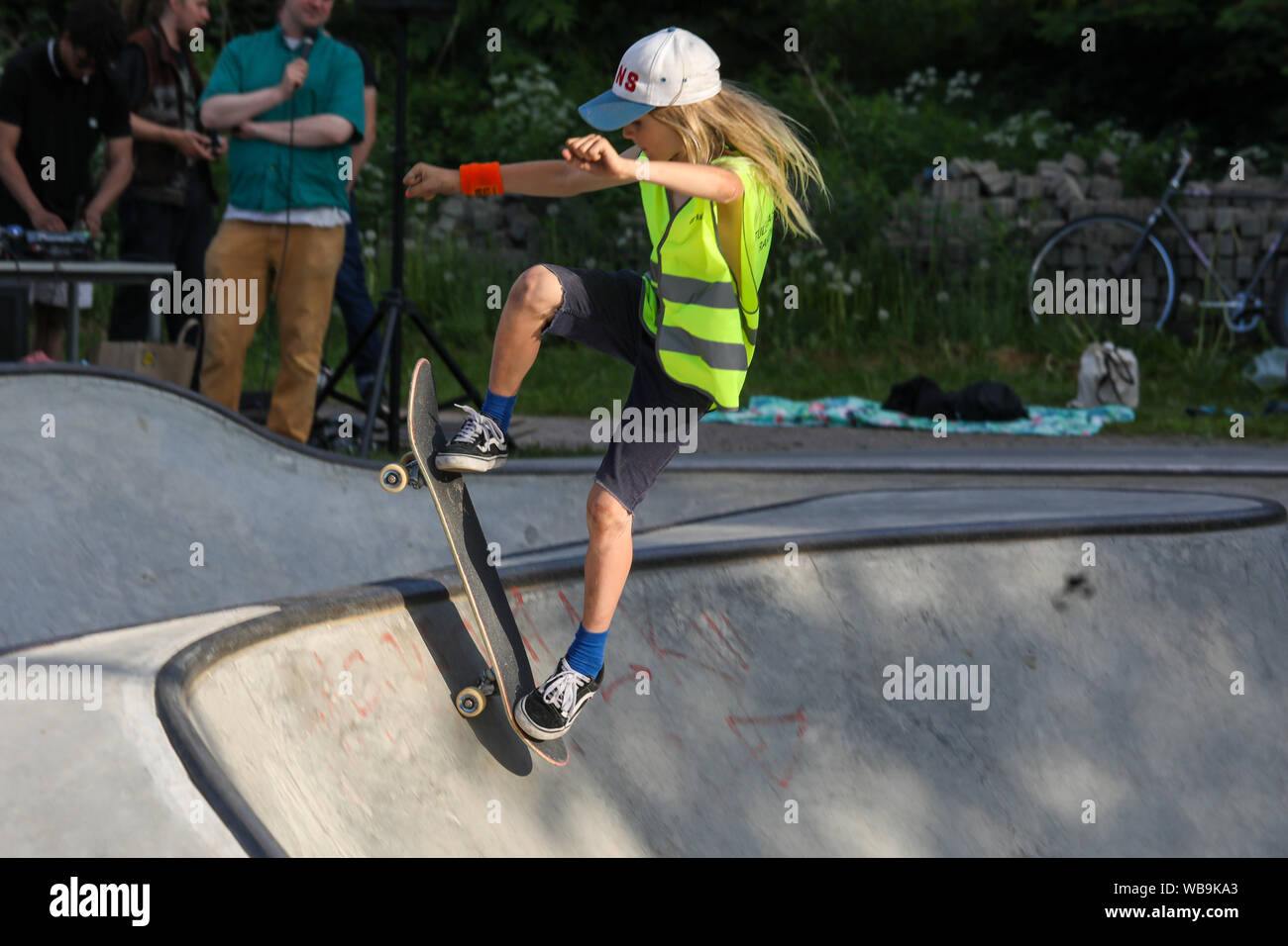 Giovani dai capelli lunghi il capretto con lo skateboard, motion congelare Foto Stock