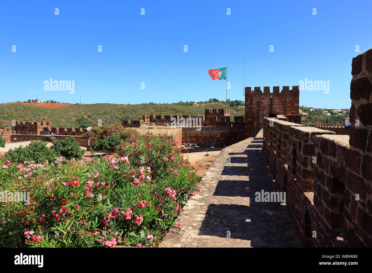 La bandiera portoghese volando sopra il castello merlature a Silves Foto Stock