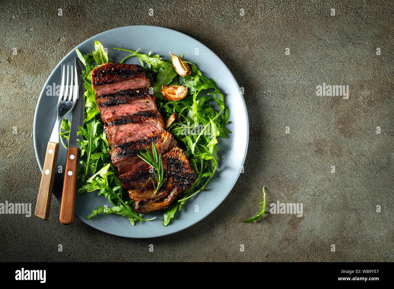 Bistecca di manzo alla griglia con vino rosso, erbe e spezie. Vista dall'alto con spazio per la copia del testo. Disposizione piatta Foto Stock