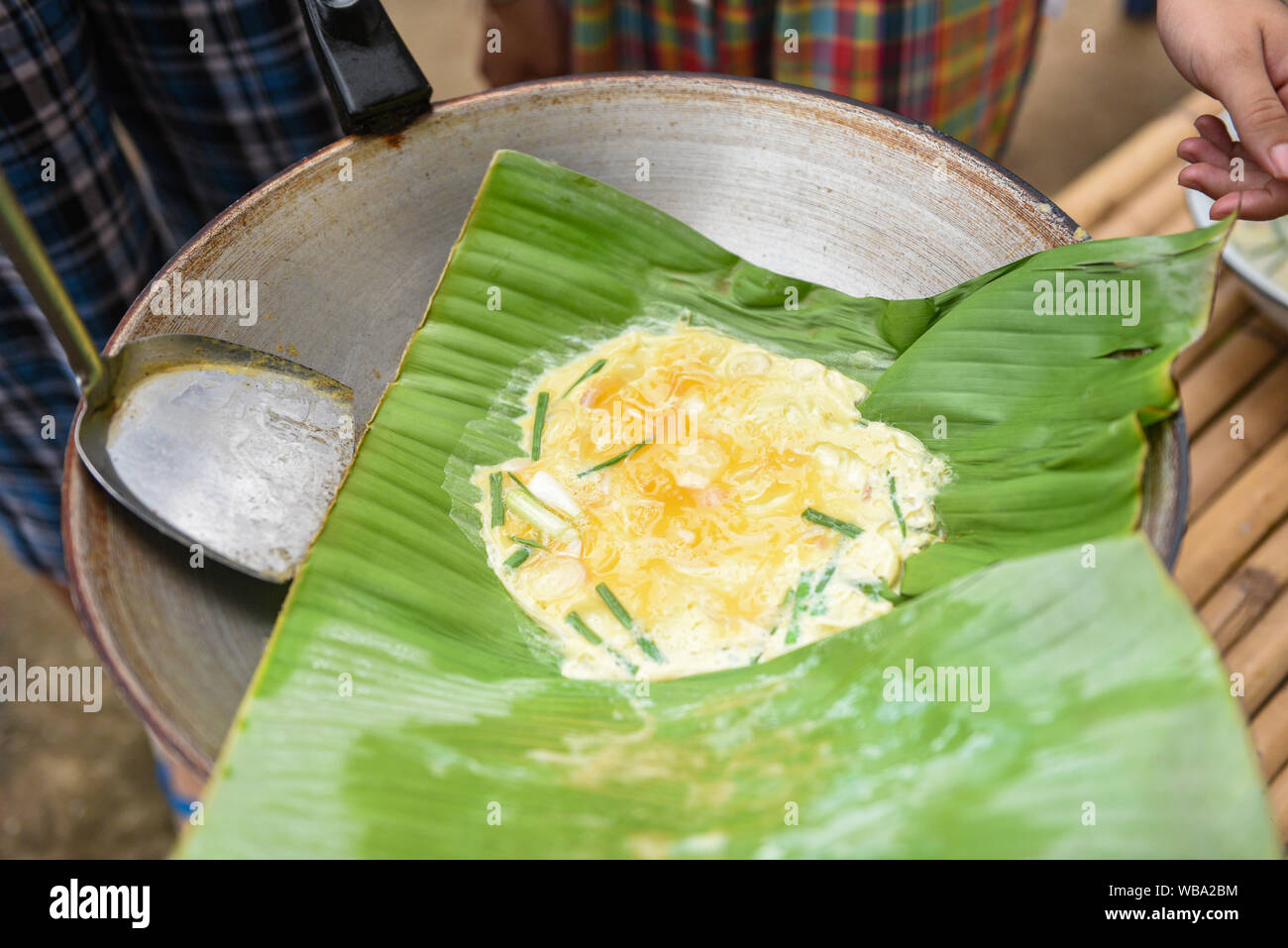 Frittata con cipolla verde in una foglia di banano sul pan prima colazione cucina Asiatica / Khai-Pam uovo fritto frittata senza olio Foto Stock