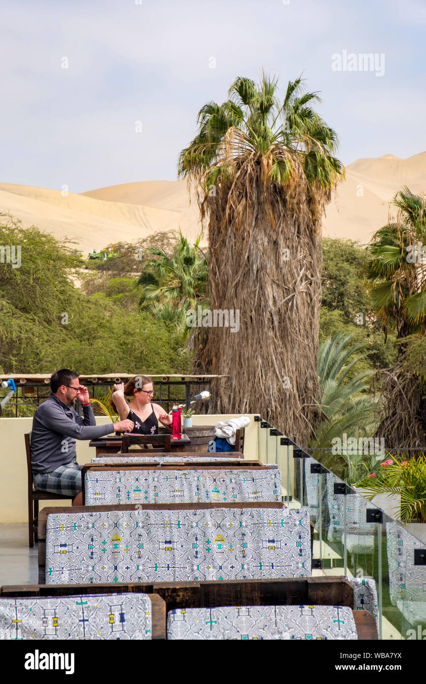 I clienti seduti sul patio esterno di Moskito bar, Huacachina oasi nel deserto, Ica, Perù Foto Stock