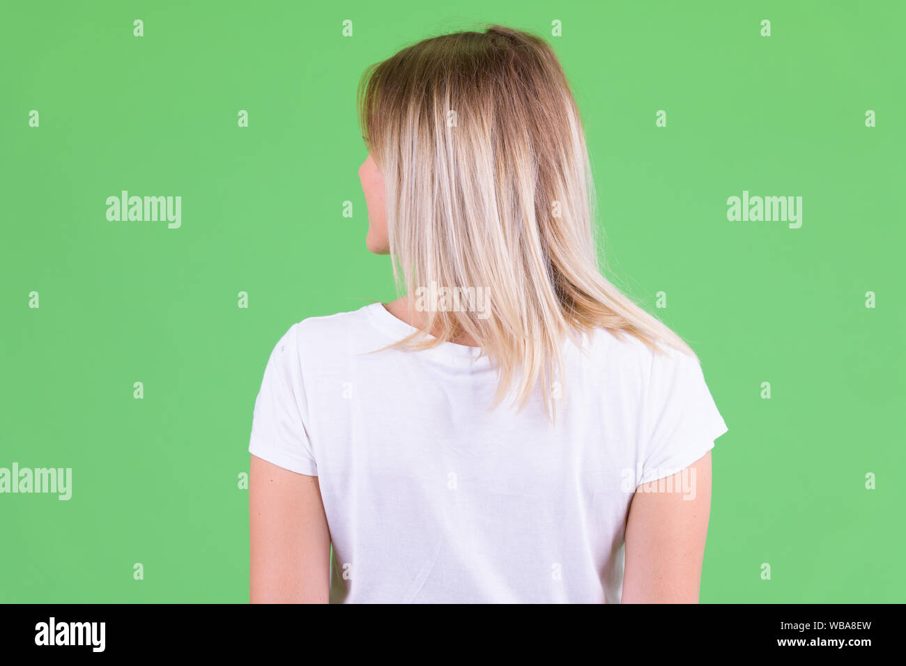 Vista posteriore del giovane donna bionda guardando sopra la spalla Foto Stock