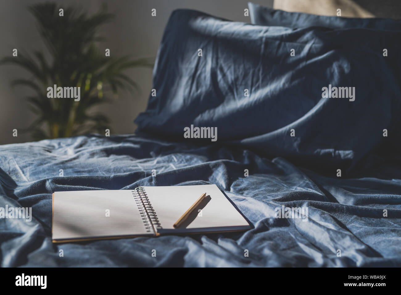 Diario del notebook su lenzuola blu; concetto di journaling o il brainstorming al mattino Foto Stock