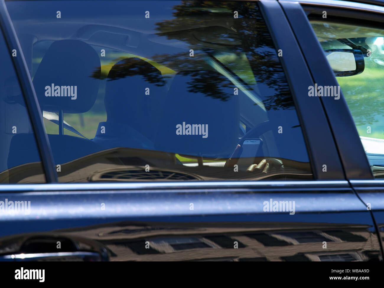 Un vero e proprio e regolari silhouette vista da altri interessati agli automobilisti di un conducente distratto dietro la ruota sms e la guida. Foto Stock