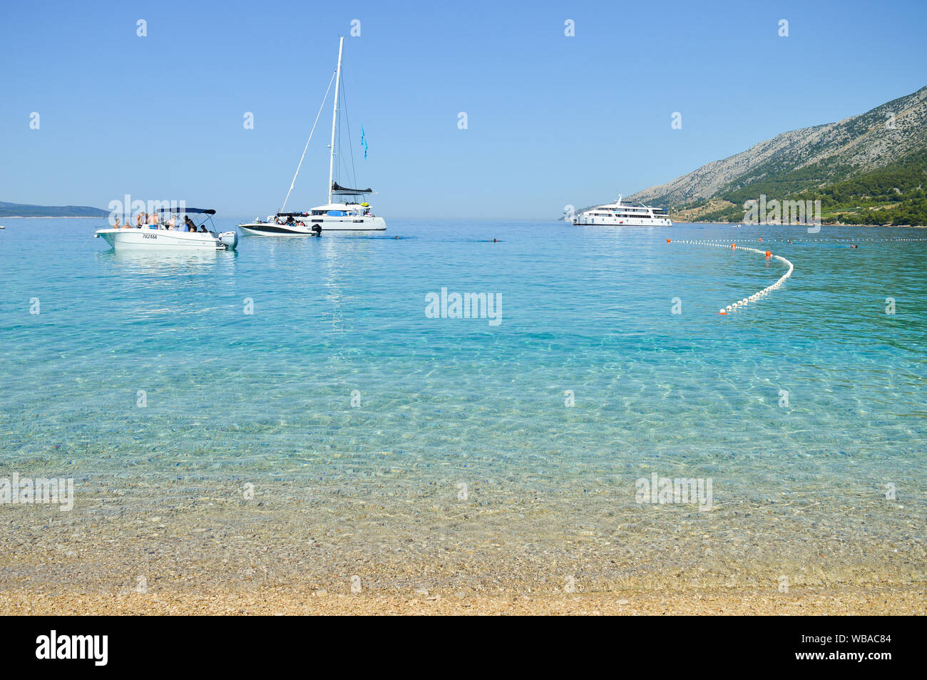Barche a vela di fronte la famosa spiaggia di ciottoli di Zlatni rat, turchese del mare colore, isola di Brac, Croazia Foto Stock