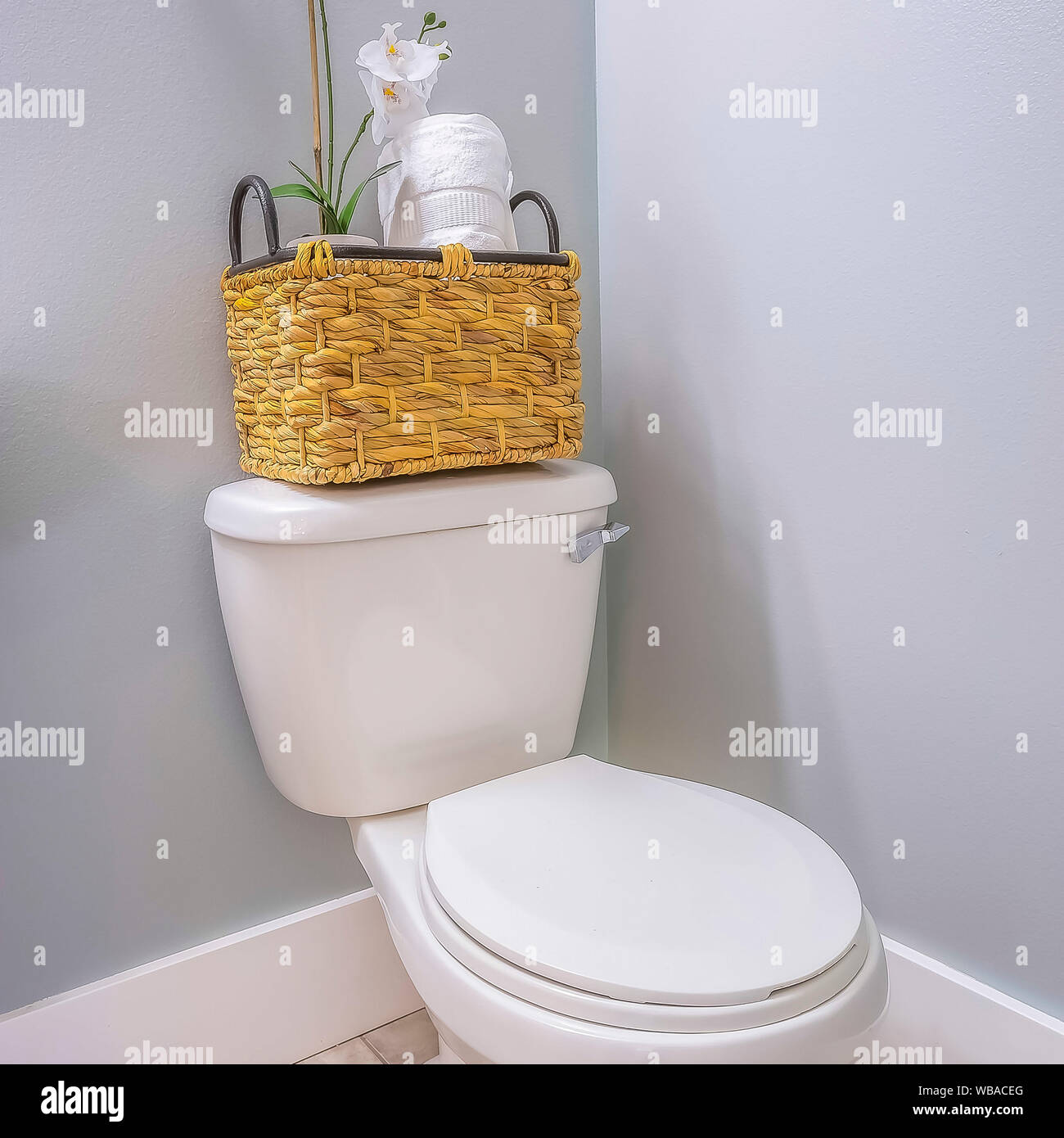 Cornice quadrata wc all'angolo di una stanza da bagno con un cesto in  rattan sulla parte superiore del serbatoio Foto stock - Alamy