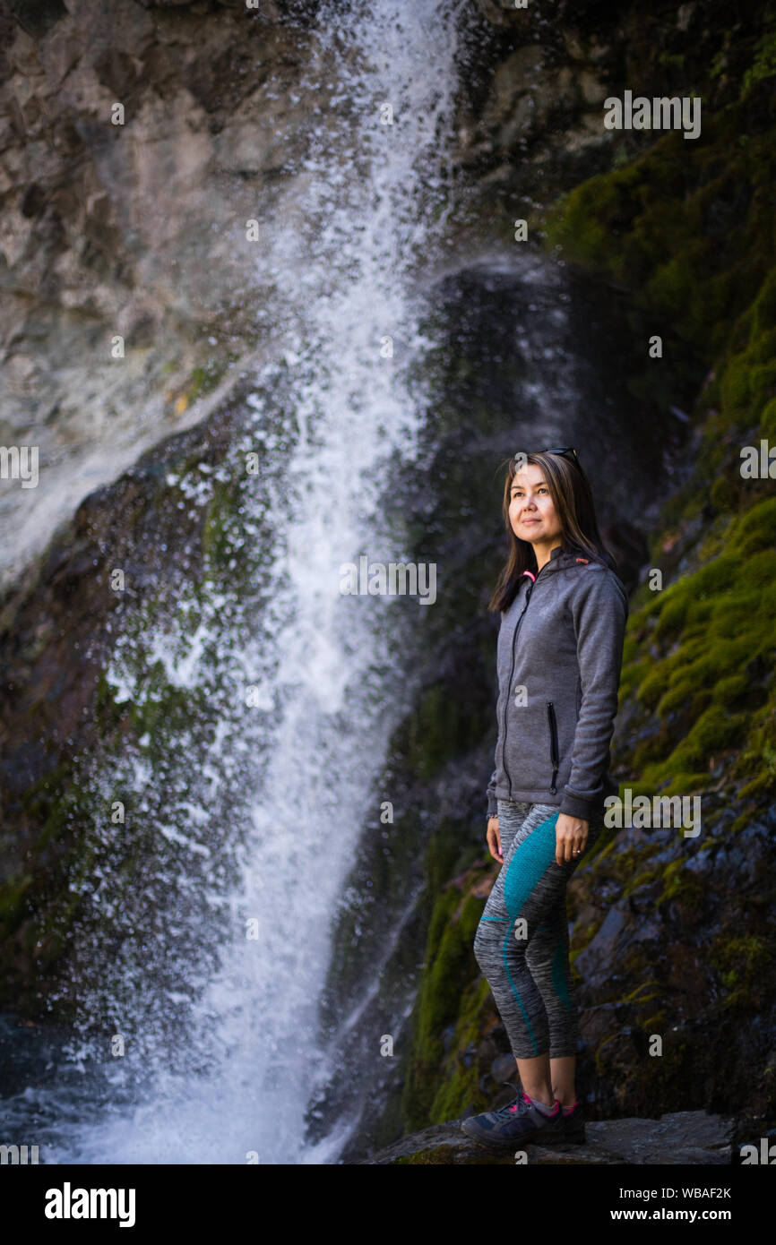 In posa accanto ad una famosa cascata nella Valle di Alameddin nel Chuy Oblast del Kirghizistan. Foto Stock