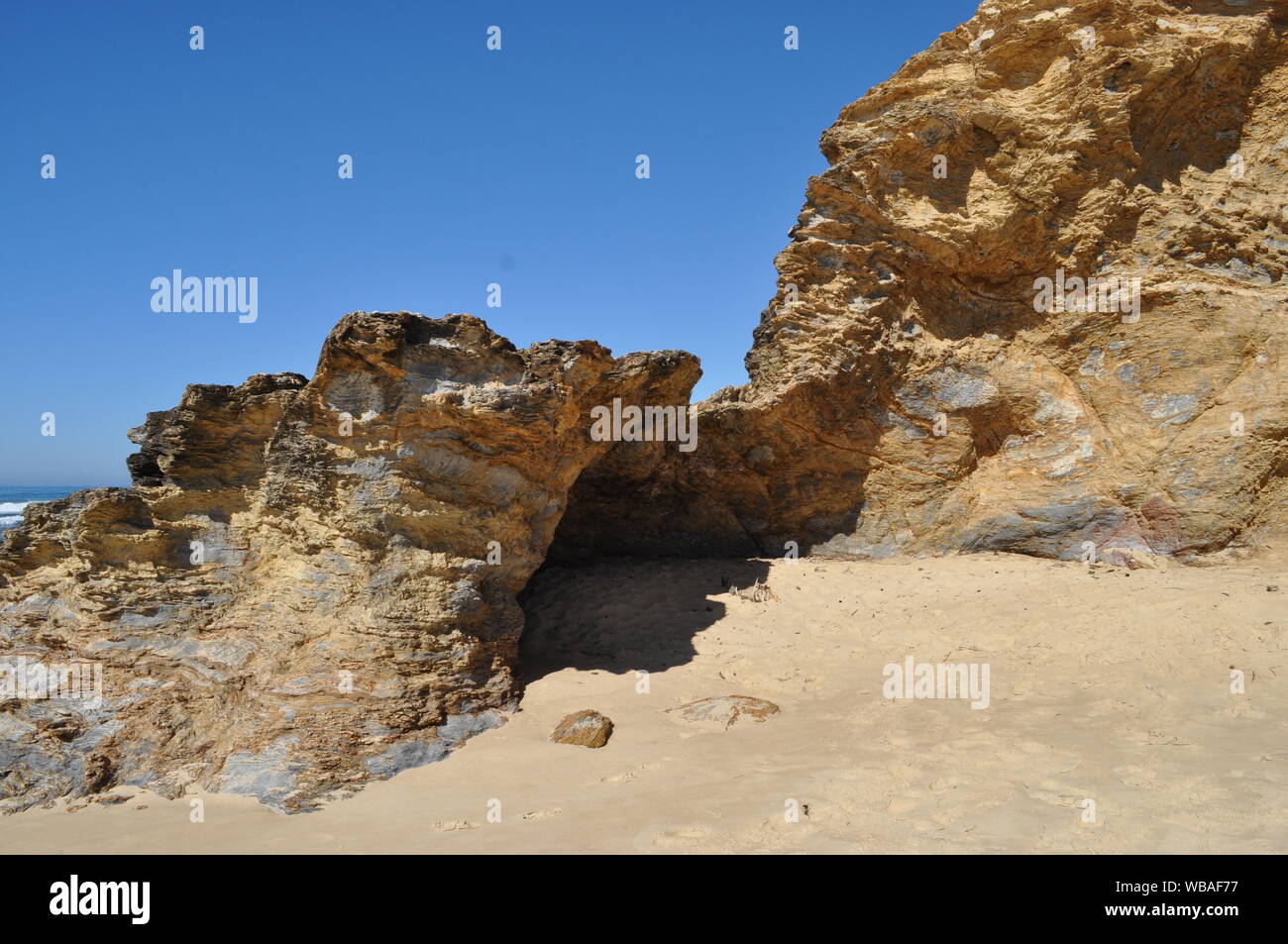 Iconici caratteristica roccia, una grotta naturale a sud di Valla Beach con cielo blu chiaro, Valla Beach, Nuovo Galles del Sud, Australia. Foto Stock