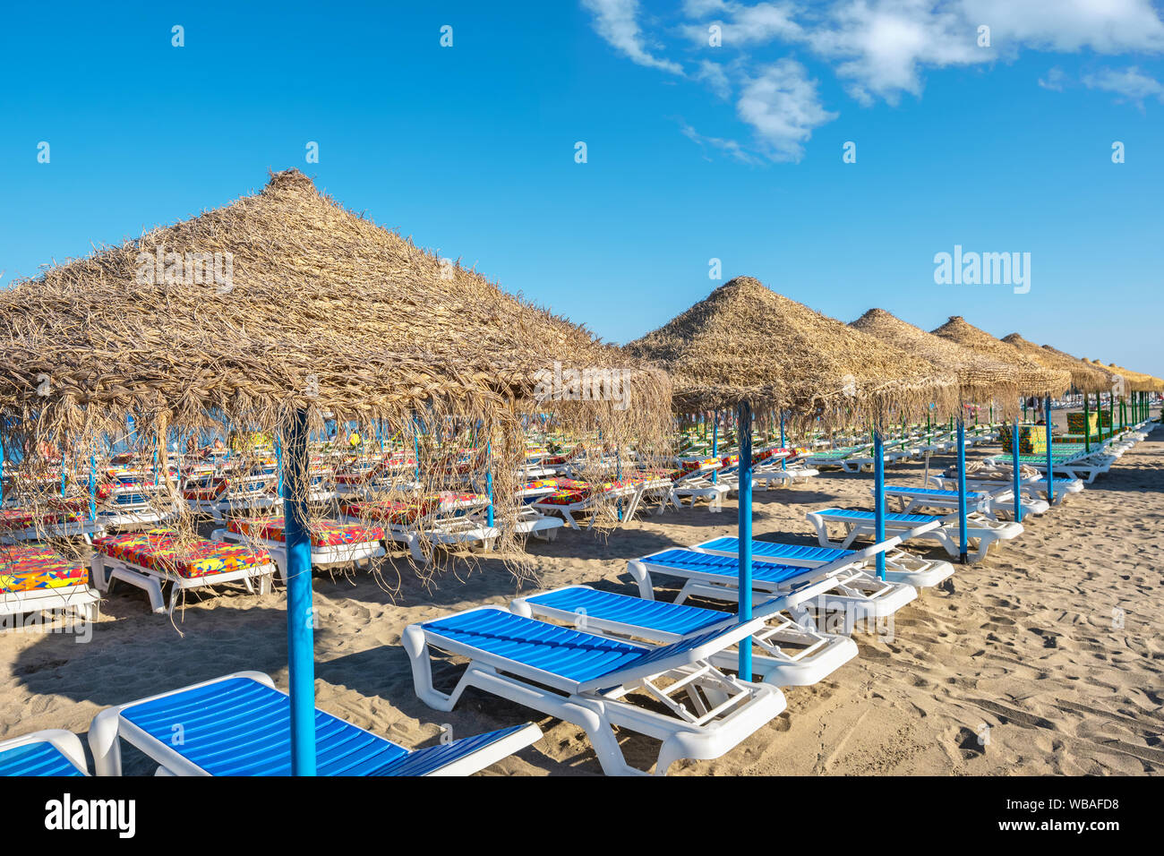 Sedie a sdraio e ombrelloni di paglia sulla spiaggia di Carihuela. Torremolinos Costa del Sol, Andalusia, Spagna Foto Stock