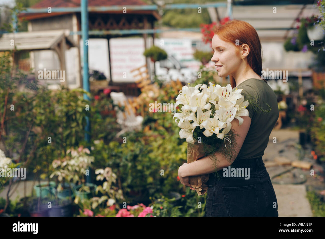 Sorridente redhead bellissima ragazza con gigli in sacchetto di carta Foto Stock