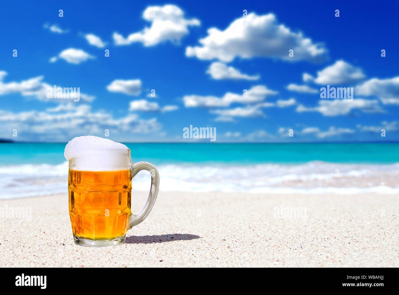 La birra in una tazza di vetro su di una spiaggia di sabbia bianca sullo sfondo Foto Stock