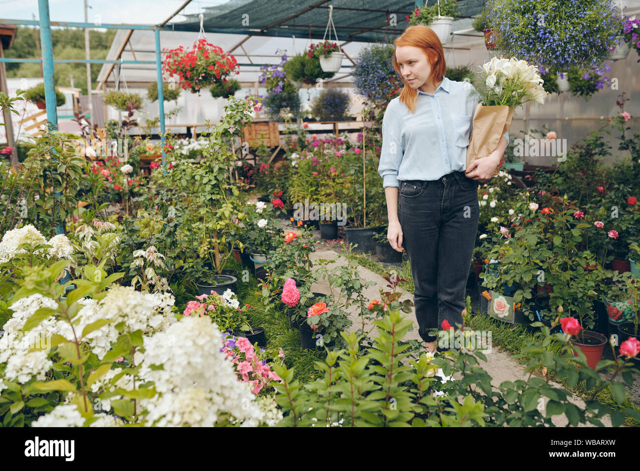 Redhead girl scelta di fiori nel giardino Foto Stock