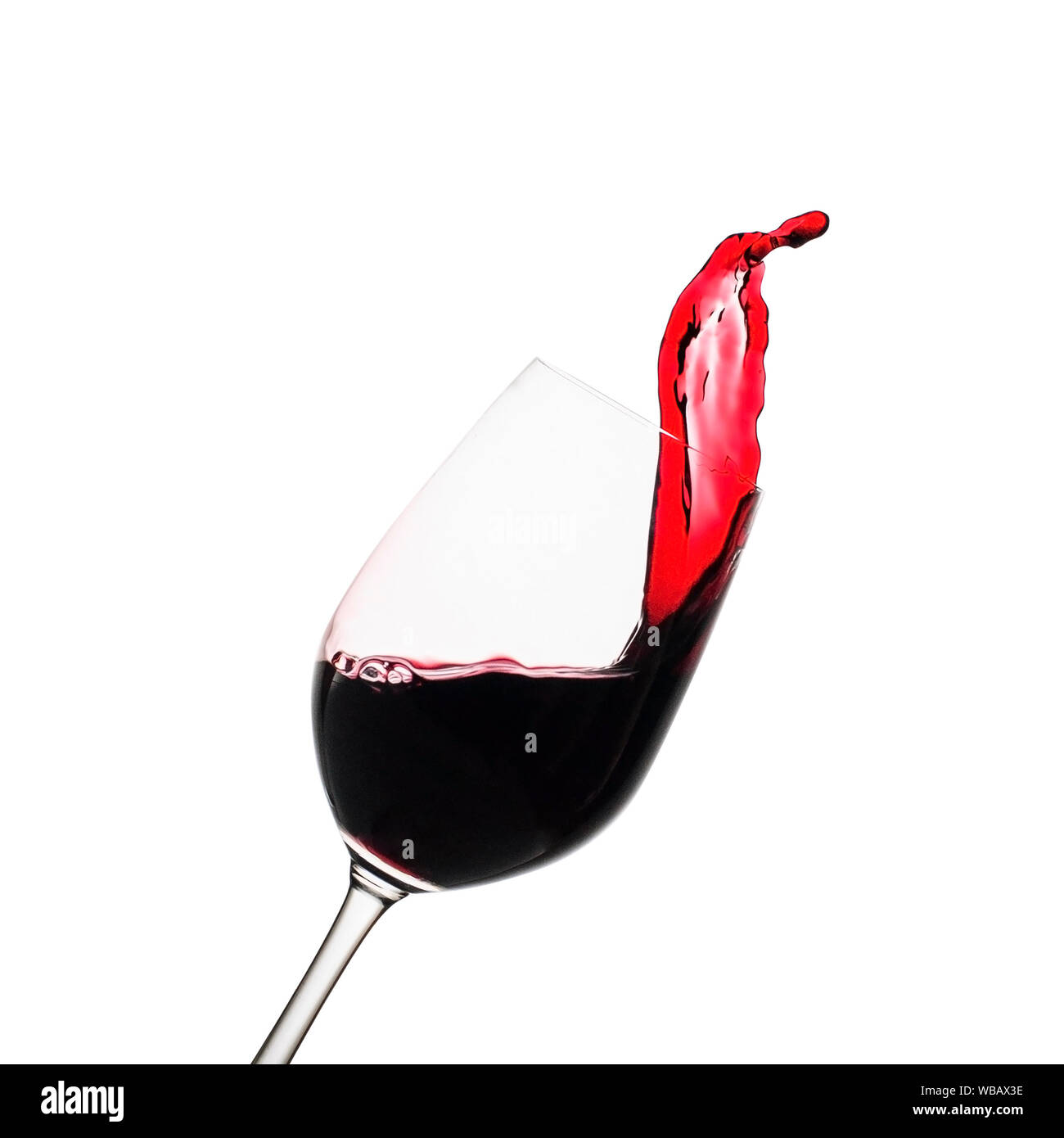 Congelare il movimento spruzzata di vino rosso in un elegante inclinato wineglass isolato su bianco con spazio di copia Foto Stock