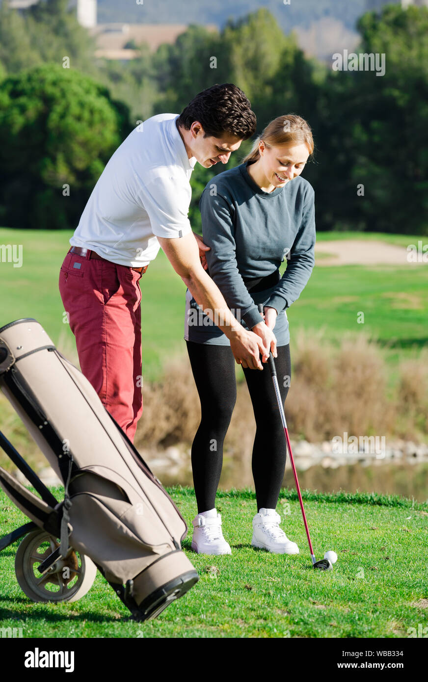 L'uomo golfista insegna una giovane donna il diritto di giocare a golf Foto Stock