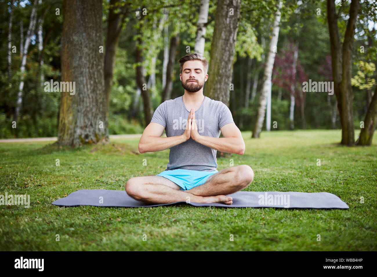 Giovane uomo in una posa meditativa nel parco Foto Stock