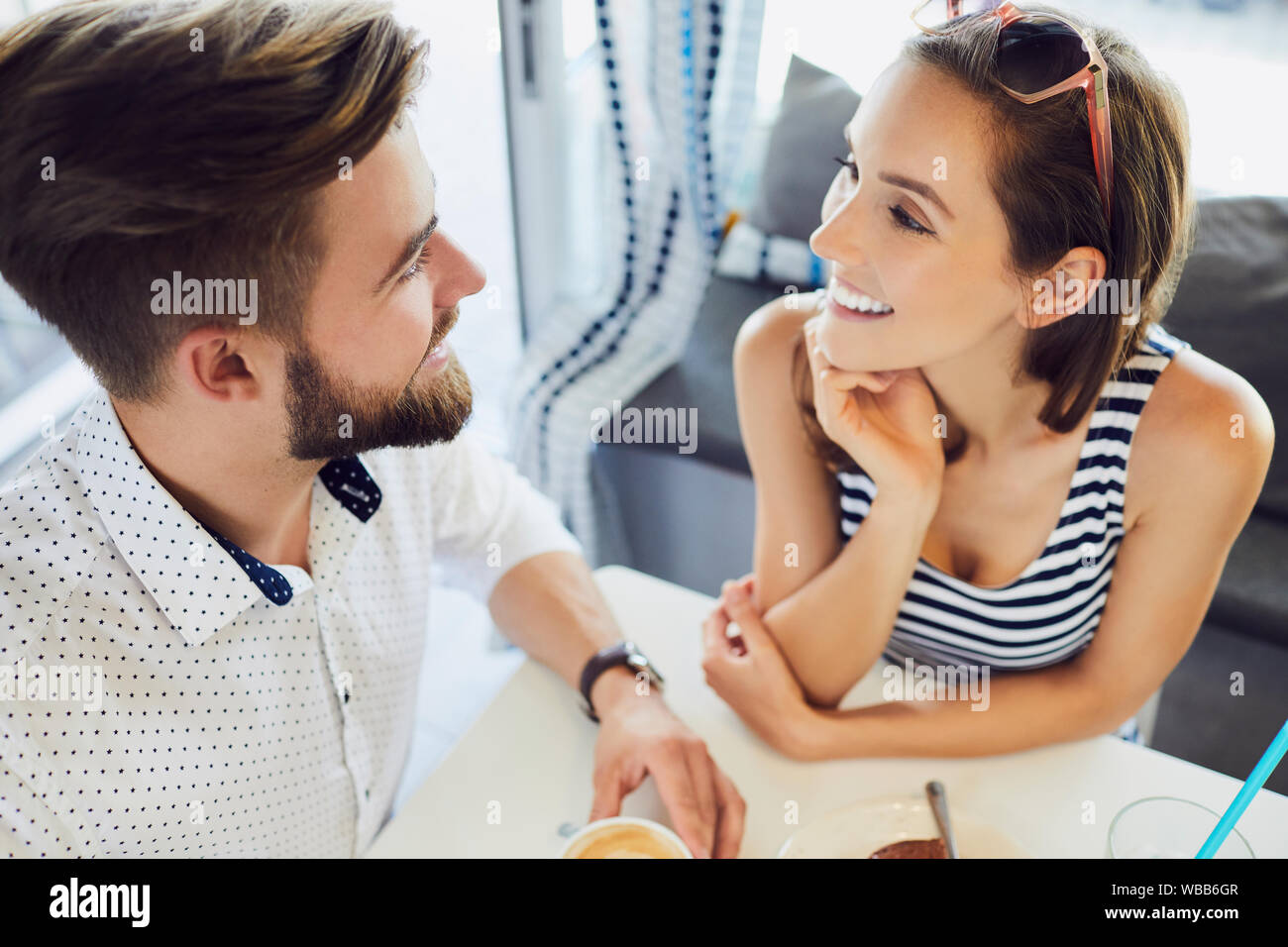 Vista superiore della coppia giovane a parlare e ridere mentre è seduto nella caffetteria rilassante e di bere il caffè Foto Stock