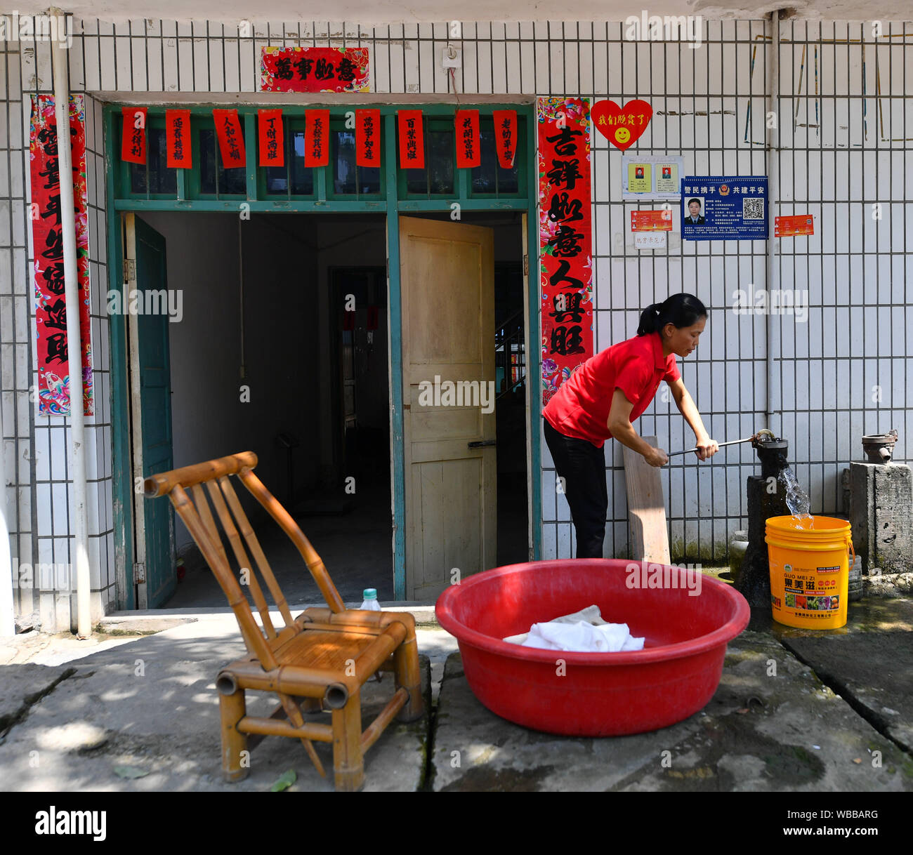 (190826) -- NANCHANG, Agosto 26, 2019 (Xinhua) -- Liu Lihong preleva acqua per lavare la biancheria di casa in Dabaidi township di Città Ruijin, Cina orientale della provincia di Jiangxi, 19 Agosto, 2019. Indossa un berretto nero e una coppia di a tacco alto scarpe, Liu Lihong stir-fritte di carne e verdure usando fornelli mentre si ascolta la musica, una scena tipica nella sua routine quotidiana. Il 40-anno-vecchio cuoco ha lavorato per il governo locale di Dabaidi township di oltre tre anni. Prima di essere un cuoco professionista, Liu era un lavoratore migrante in una fabbrica di abbigliamento in Shantou del sud della Cina di Provincia di Guangdong poiché t Foto Stock