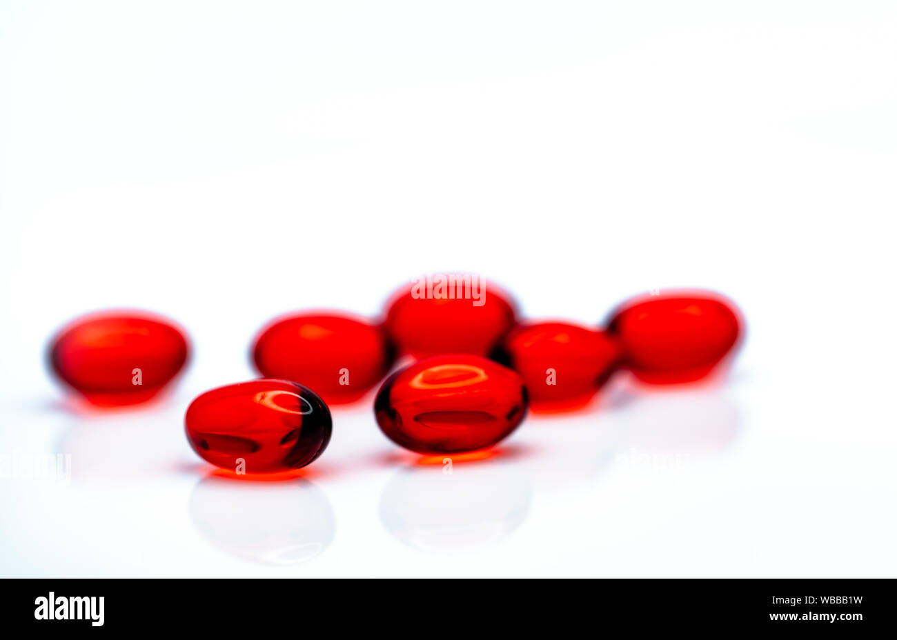 Morbido rosso capsula di gel pillole isolati su sfondo bianco. Pila di red capsule di gelatina morbida. Vitamine e integratori dietetici concetto. Prodotti farmaceutici Foto Stock