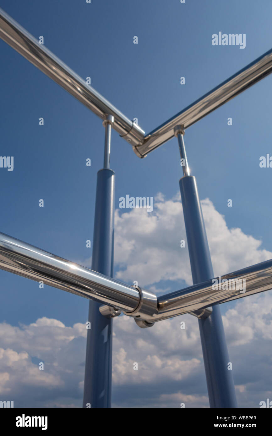 Acciaio inossidabile ringhiera scale dall'esterno dell'edificio su uno sfondo di cielo blu e nuvole bello. Tubi, cerniere, balaustre fatta di sta Foto Stock