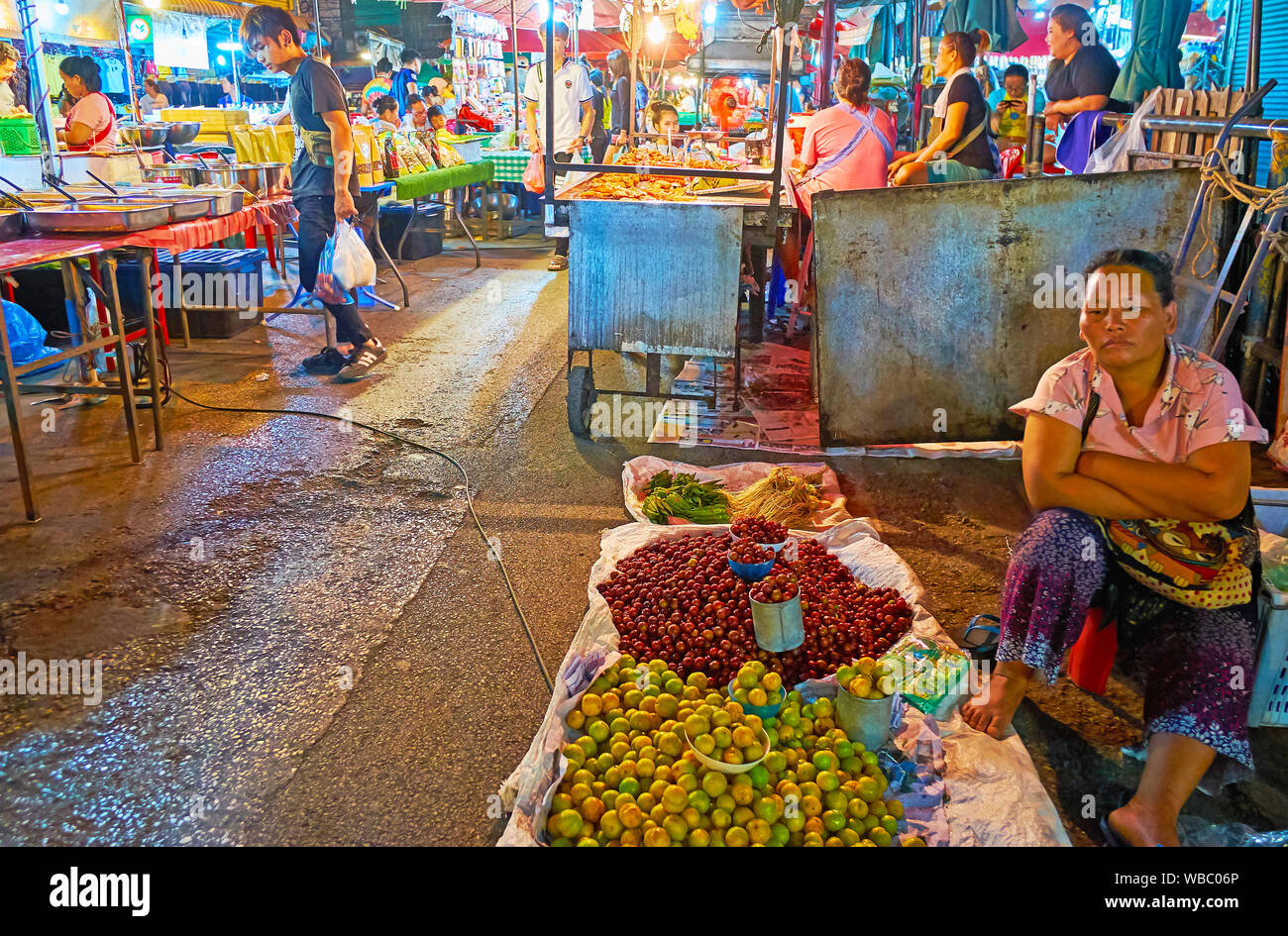 CHIANG MAI, Thailandia - 2 Maggio 2019: Il venditore è annoiato, seduta sul pavimento a cumuli di prugna e ciliegia-susine nel mercato Warorot, il 2 maggio in ch Foto Stock
